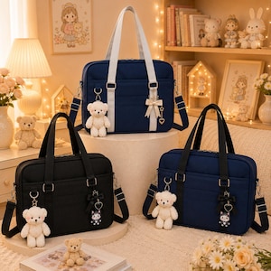 Può includere: Tre borse a tracolla rettangolari in blu navy e nero, ciascuna dotata di due manici superiori, una tracolla rimovibile e un portachiavi a forma di orsetto di peluche. Le borse sono decorate con piccoli fiocchi e ciondoli.