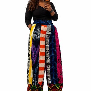 Puede incluir: Pantalones de pierna ancha con un diseño de patchwork vertical que incluye varios patrones coloridos, como rayas naranjas, formas geométricas azules y motivos florales rosas, rematados con un dobladillo multicolor vibrante.