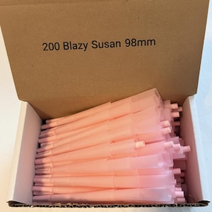 May include: A cardboard box filled with numerous pink pre-rolled cones. The box has the text "200 Blazy Susan 98mm" printed on the top. The cones are neatly arranged inside the box, ready for use.