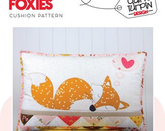 May include: A pink and white cushion with a brown and orange fox sleeping on it. The fox is dreaming of a pink heart. The cushion has a patchwork design on the bottom.