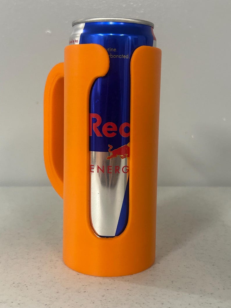 May include: An orange can cooler with a handle holds a Red Bull energy drink can. The can is blue and silver with the Red Bull logo and text. The cooler is made of plastic.