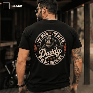 May include: A black t-shirt featuring a circular graphic on the back. The design includes a gorilla wearing sunglasses and a leather jacket, surrounded by the text: THE MAN THE MYTH DADDY THE BAD INFLUENCE, accented with stars and lightning bolts.