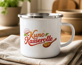May include: A white enamel mug with a silver rim and a handle, featuring a graphic design that includes the text Kuno Kasserolle, a pink chef hat, green herbs, and a wooden spoon filled with peas and corn, all printed on the front surface.