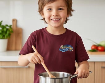 May include: A maroon short-sleeved t-shirt featuring a graphic on the chest with the text "Die Mitternachts Köche" in a stylised font, accompanied by an illustration of a cooking pot under a crescent moon and stars against a blue background.