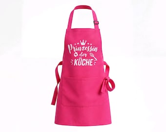 May include: A bright pink apron featuring a white graphic print on the chest. The design includes a crown icon, a whisk, a spoon, and the German text "Prinzessin der KÜCHE". The apron has an adjustable neck strap and a large front pocket.
