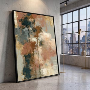May include: A large rectangular wall art piece in a black frame featuring an abstract painting with layered brushstrokes in shades of terracotta, deep teal, cream, and metallic gold, displayed leaning against a concrete wall in a room.