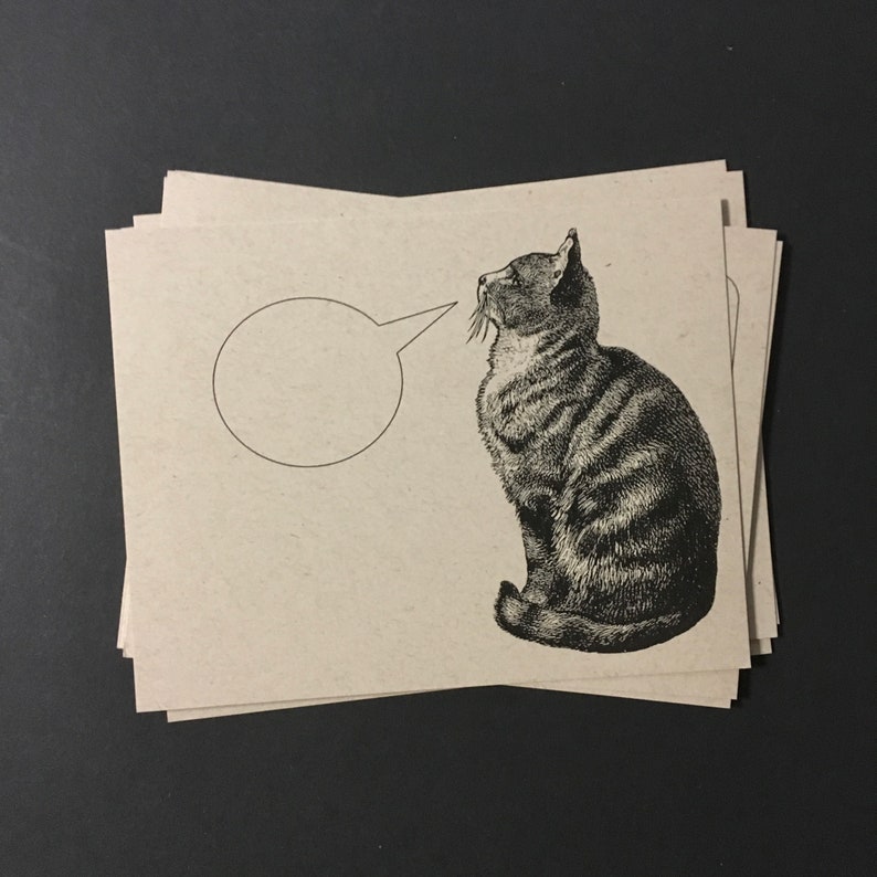 May include: A black and white illustration of a cat looking to the left with a speech bubble above its head. The speech bubble is empty.