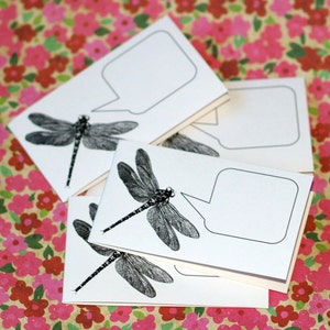 May include: Set of four blank note cards featuring a black and white dragonfly illustration with a speech bubble. The cards are perfect for writing notes, messages, or reminders.