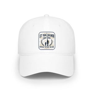 May include: A white baseball cap with a curved peak. The cap has a rectangular patch with the text "LET YOUR CHILDREN SEE GOD IN YOU BY THE WAY YOU LIVE." The patch shows a parent and child silhouette.