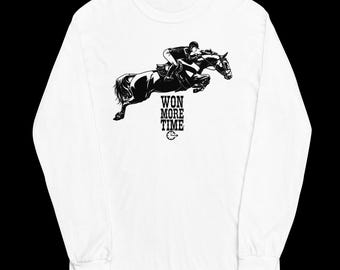 May include: A white long-sleeve shirt featuring a black graphic of a rider on a horse jumping over an obstacle. Below the horse, the text reads WON MORE TIME, accompanied by a small clock icon. The design is centered on the chest of the shirt.
