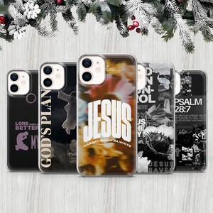 May include: A collection of phone cases with various designs and text. One case features the word "JESUS" in large white letters with "HAS MY BACK ALWAYS" below. Other cases display religious imagery and phrases like "GOD'S PLAN" and "PSALM 28:7".