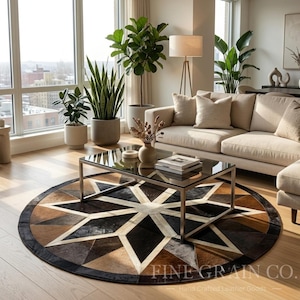 May include: A circular area rug featuring a geometric star pattern composed of stitched leather panels in shades of black, dark brown, and cream. The rug has a dark border and is positioned on a light wood floor beneath a glass coffee table.