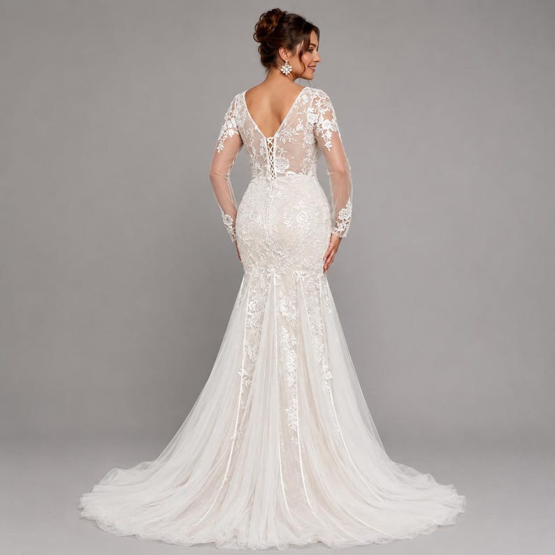 May include: A floor-length white wedding dress featuring long sheer lace sleeves, a deep V-shaped back with lace-up corset detailing, and an intricate floral lace overlay that extends into a flared tulle skirt with a train.