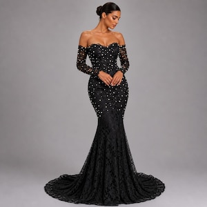 May include: A black, off-the-shoulder formal gown with long sleeves. The dress is made of lace and has a mermaid silhouette with a long train. Small white pearls are scattered across the bodice and skirt.