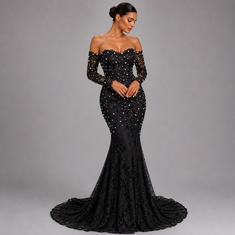 May include: A black, off-the-shoulder formal gown with long sleeves. The dress is made of lace and has a mermaid silhouette with a long train. Small white pearls are scattered across the bodice and skirt.