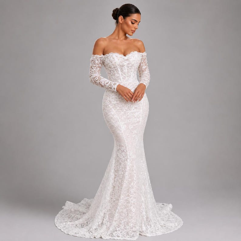 May include: A white, off-the-shoulder wedding dress with long sleeves. The dress is made of lace and has a mermaid silhouette, fitted through the bodice and flaring out from the knees. The dress features a sweetheart neckline and a train.