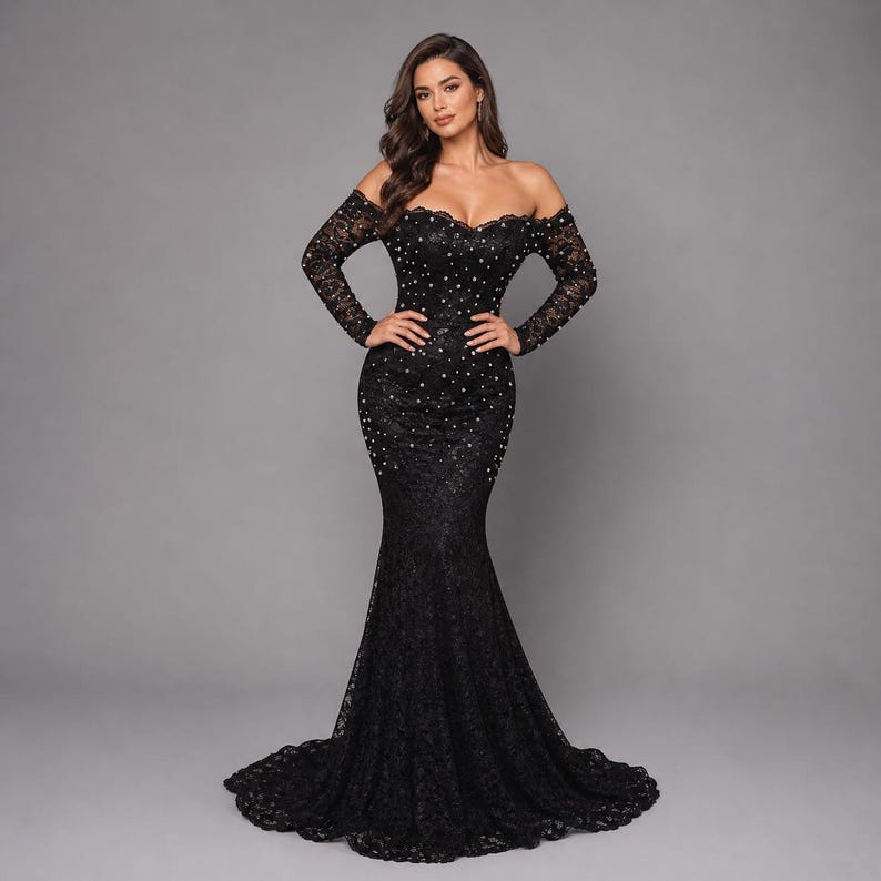 May include: A black, off-the-shoulder, floor-length gown with long sleeves. The dress is made of lace and embellished with sparkling accents. The gown has a mermaid silhouette, fitted through the bodice and flaring out at the knees.