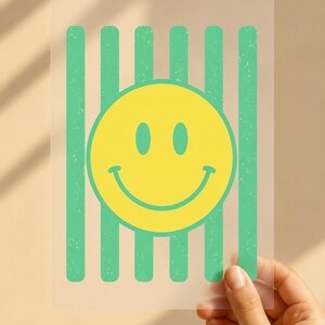 Könnte beinhalten: Ein rechteckiges, durchscheinendes Blatt mit einer zentrierten gelben Smiley-Grafik, die über einer Reihe vertikaler grüner Streifen liegt. Die grünen Streifen haben eine abgenutzte Textur, während das gelbe Smiley-Gesicht einfarbig und glatt ist.