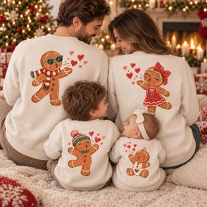 Könnte beinhalten: Ein Set aus vier passenden cremefarbenen Rundhals-Sweatshirts mit Lebkuchenmann-Grafiken. Jedes Oberteil zeigt eine Lebkuchenfigur, die rote Herzen bläst, darunter Varianten mit Sonnenbrille, Schleife, Mütze oder Windel, die jeweils auf dem Rücken der Kleidung abgebildet sind.