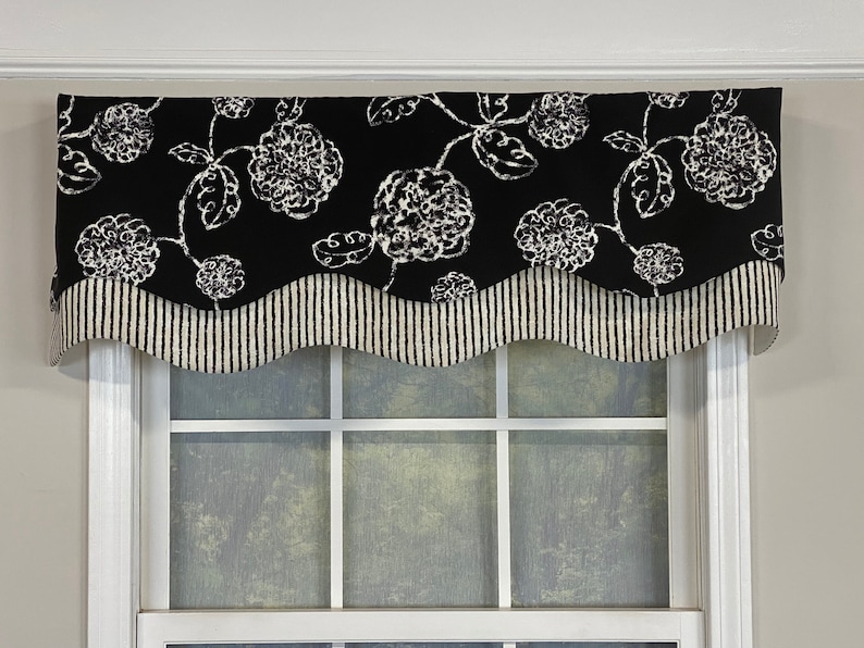 May include: Black and white valance with a scalloped edge and a floral pattern. The valance is made of fabric and has a striped bottom border.