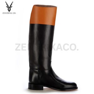 May include: A black leather riding boot with a tan leather section at the top. The boot features a classic design with a low heel and a smooth finish. The brand name "ZENTRIXA CO." is printed on the side.