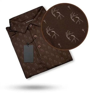 May include: A dark brown polo shirt featuring a repeating pattern of light-colored deer antlers and small circular icons. The shirt has a classic collar, a three-button placket, and a blank rectangular tag attached to the front chest area.