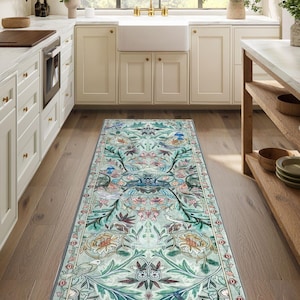 Puede incluir: Una alfombra rectangular con un diseño floral y de pájaros en tonos turquesa, verde y rosa. La alfombra está colocada sobre un suelo de madera en una cocina. El diseño presenta flores y pájaros estilizados.