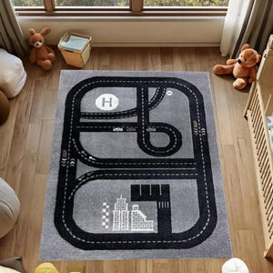 May include: A gray rectangular play rug with a black road design. The rug features a helipad, city skyline, and road markings. The rug is designed for children's play and measures approximately 60 inches by 40 inches.