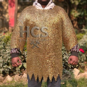 May include: A gold-colored chainmail shirt with a hooded neckline and long sleeves. The shirt has a jagged hemline and is worn over a black long-sleeve shirt with patterned cuffs. The image has the text "HCS" in the center.