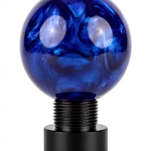 May include: A spherical gear shift knob featuring a deep blue, swirling pearlescent resin finish. The top section is a smooth, glossy sphere, while the base consists of a black, cylindrical metal mount with visible threading for installation.