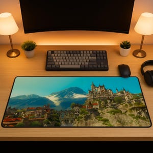May include: A rectangular mouse pad featuring a scenic landscape with a mountain, a castle, and a town. The pad is black-edged and rests on a wooden desk, with a keyboard, mouse, and other accessories.