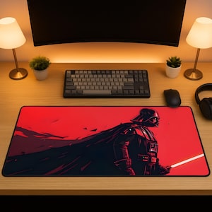 Könnte beinhalten: Rechteckiges rotes Mauspad mit einer stilisierten Illustration von Darth Vader mit einem Lichtschwert. Das Kunstwerk ist hauptsächlich schwarz und rot, mit einem schwarzen Rand. Das Pad liegt auf einem Holzschreibtisch, zusammen mit einer Tastatur, einer Maus und anderem Zubehör.