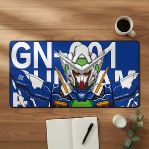 Può includere: Un tappetino da scrivania rettangolare blu con un'illustrazione dettagliata di un robot Gundam. Il tappetino presenta un testo bianco che recita "GN-001 GUNDAM" e altri dettagli tecnici. Il robot è principalmente blu, bianco, verde e rosso.