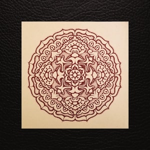 Peut inclure: Un motif de mandala détaillé à l'encre rouge foncé sur un carré de papier blanc cassé. Le motif complexe présente des éléments floraux et géométriques, avec un motif central circulaire et des bordures ornées. Le papier est posé sur un fond noir.