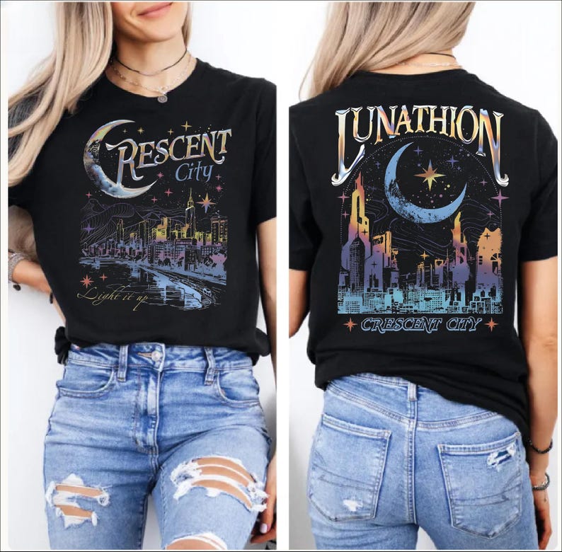 May include: A black short-sleeve t-shirt featuring a graphic print of a city skyline, a crescent moon, and stars. The front displays the text Crescent City and Light it up. The back features the text Lunathion and Crescent City.