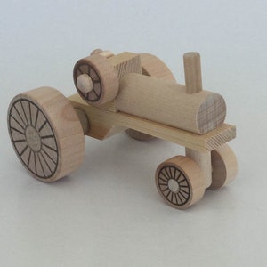 K&ouml;nnte beinhalten: Ein h&ouml;lzerner Spielzeugtraktor mit vier R&auml;dern. Die R&auml;der haben ein Sonnenstrahl-Design. Der Traktor ist aus Naturholz gefertigt und hat ein schlichtes Design.
