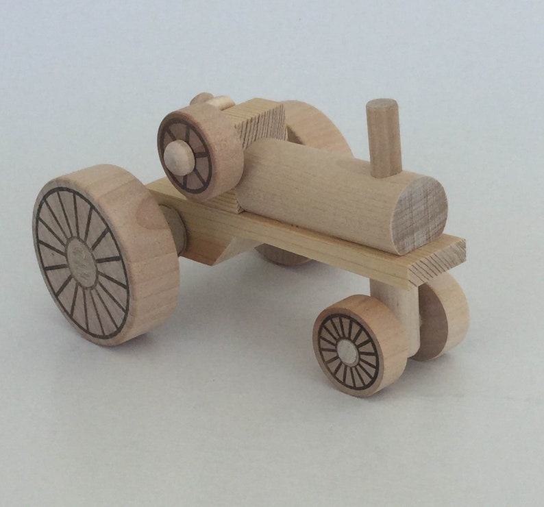K&ouml;nnte beinhalten: Ein h&ouml;lzerner Spielzeugtraktor mit vier R&auml;dern. Die R&auml;der haben ein Sonnenstrahl-Design. Der Traktor ist aus Naturholz gefertigt und hat ein schlichtes Design.