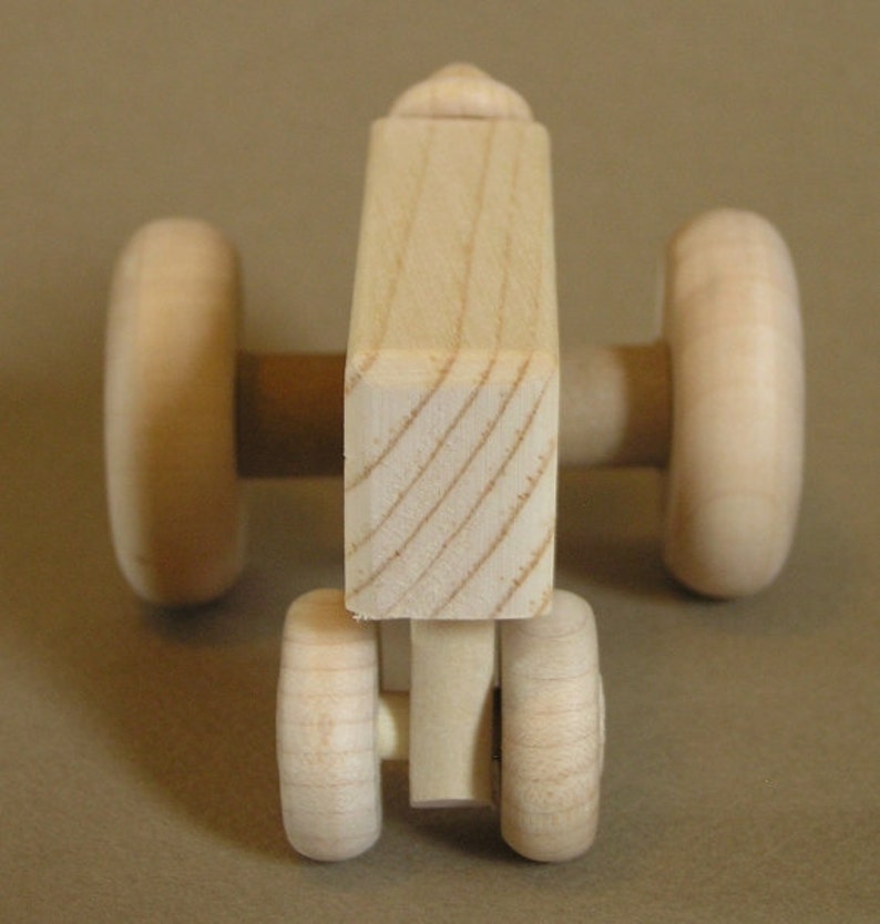 Op de afbeelding: Een houten speelgoedtractor met vier wielen. De tractor is gemaakt van natuurlijk hout en heeft een eenvoudig ontwerp.