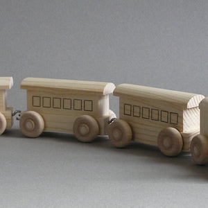 May include: A wooden toy train set with an engine, a caboose, and two passenger cars. The train is made of unfinished wood and has black painted details.