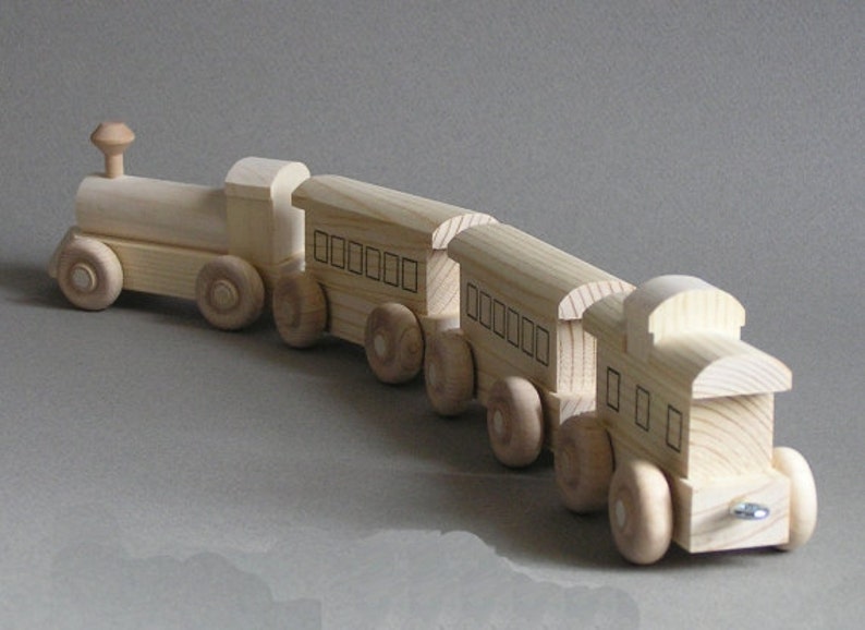 May include: A wooden toy train set with a locomotive and three cars. The train is made of natural wood and has a simple design. The cars have windows and are connected to each other by metal couplers.