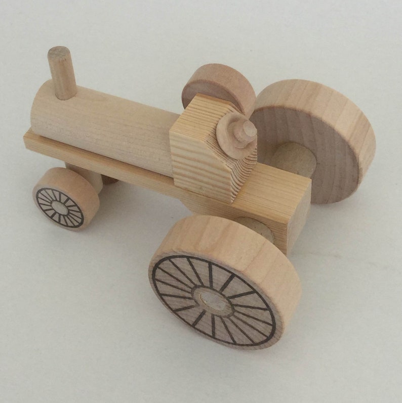 K&ouml;nnte beinhalten: Ein h&ouml;lzerner Spielzeugtraktor mit vier R&auml;dern. Die R&auml;der haben ein einfaches Design mit Speichen. Der Traktor ist aus unbehandeltem Holz.
