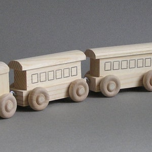 May include: A wooden toy train set with an engine, a caboose, and three passenger cars. The train is made of natural wood and has a simple, classic design.