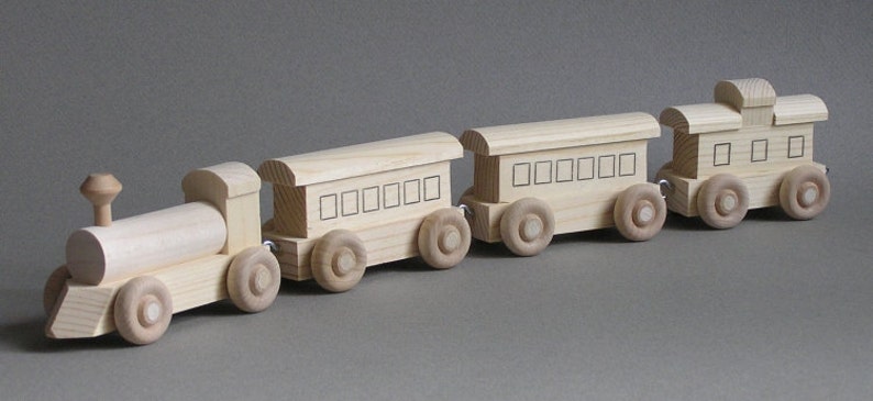 May include: A wooden toy train set with an engine, a caboose, and three passenger cars. The train is made of natural wood and has a simple, classic design.