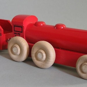 May include: A red wooden toy train with a black star on the side and a wooden boxcar that says "OMAHA" on the side. The train has five wooden wheels.