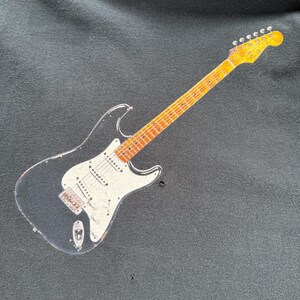 Pu&ograve; includere: Felpa nera con grafica di una chitarra elettrica vintage. La chitarra ha un corpo nero, battipenna bianco e manico e paletta gialli. La felpa &egrave; realizzata in un tessuto morbido e scuro.