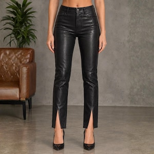 May include: High-waisted black trousers with a glossy, leather-effect finish. These fitted trousers feature a straight-leg cut and a distinct vertical slit at the centre of each ankle hem, complete with a standard button and zip fly closure.