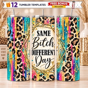 May include: Three cylindrical tumblers featuring a leopard print pattern with vibrant blue, pink, and yellow paint drips. The center tumbler displays the black text "SAME Bitch DIFFERENT Day" inside a gold geometric frame with a small heart icon.