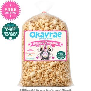 May include: A clear plastic bag filled with kettle corn labeled Okavrae Sweet Possum. The label features a cartoon opossum, text stating White Chocolate With Marshmallows And Vanilla, and a net weight of 4 oz (113g). The popcorn is light tan.