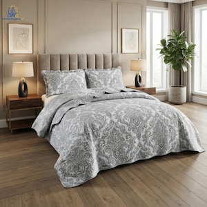 May include: A grey and white damask patterned quilt set featuring two matching pillow shams. The bedding is displayed on a bed with a tufted headboard, flanked by two wooden nightstands with black lamps and framed line art prints on the wall.