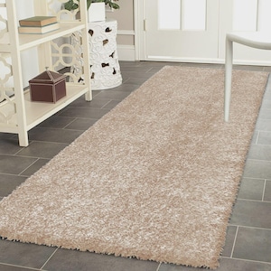 May include: A rectangular runner rug featuring a thick, shaggy pile in a solid light beige colour. The rug has a dense, textured surface with long fibres that create a soft, plush appearance across the entire length of the floor covering.